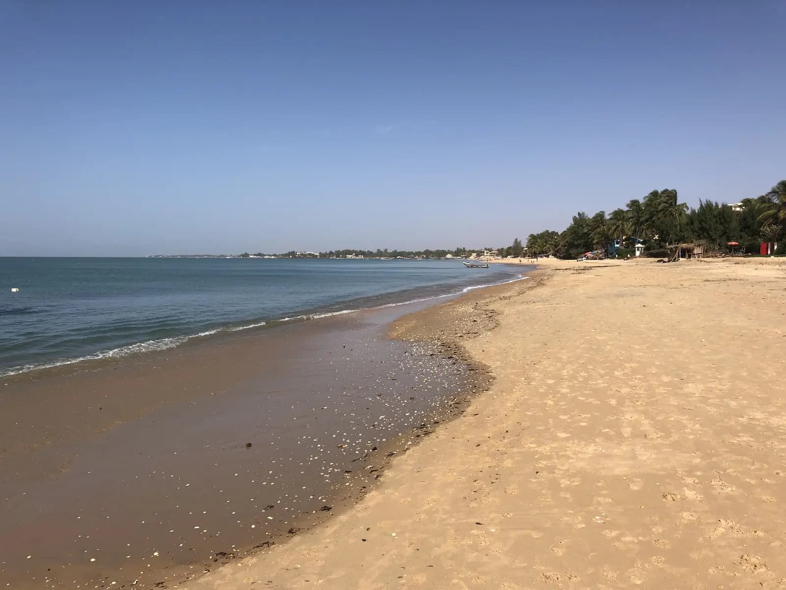 La plage de Saly Portudal, sable clair et mer calme sous un ciel degage