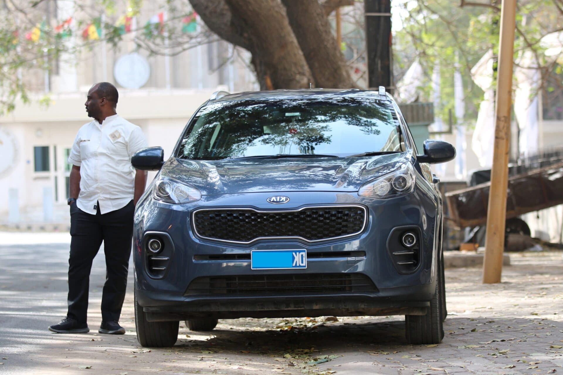 Chauffeur Dakar VTC devant un Kia Sportage de la flotte, dans une rue de Dakar